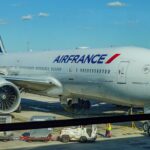 Air France airplane parked on the tarmac at an airport terminal under a clear blue sky.