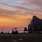 A vibrant sunset over the Phi Phi Islands beach with boats and stunning cliffs.